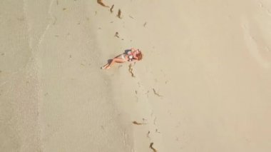Kumsalda denizde plaj havadan görünümü yalan bikinili güzel bir kadın. Seksi kadın yaz plaj, dalgalar deniz ve kum arka plan üzerinde bronzlaşma. Cennet plaj üzerinde dinlenme üstten görünüm kız.