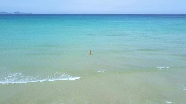 Luftaufnahme Frau, die im blauen Meer schwimmt. Drohne Ansicht Frau in türkisfarbenem Meer auf blauem Skyline-Hintergrund. — Stockvideo