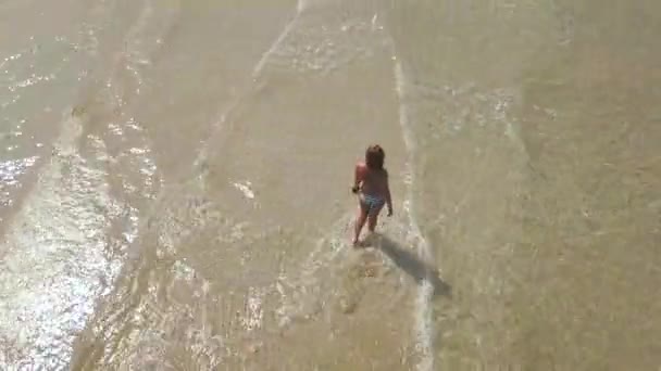 Młoda kobieta w bikini spaceru na plaży latem w przejrzyste morze woda drone. Zobacz z góry szczęśliwą kobietą w turkusowe morze woda. — Wideo stockowe