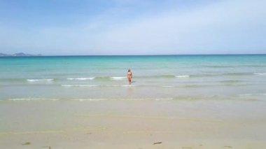 Mavi deniz manzarası arka plan üzerinde bikinili genç kadın. Cennet plaj turkuaz denizde dron görünümü kadında.