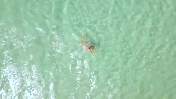 Vista dall'alto donna nuotare in acqua di mare cristallina. Donna che fa il bagno in acqua turchese mare sulla spiaggia paradiso. Vista dall'alto dal drone volante . — Video Stock