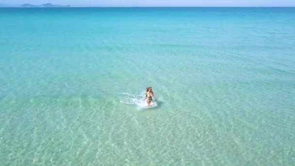 ターコイズ ブルーの海水空中ビューで実行してビキニで美しい女性。パラダイス ビーチ上で透明と透明な水でドローン ビュー幸せな女. — ストック動画