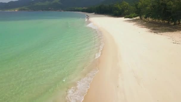 Mar azul y playa de arena paisaje aéreo. Drone volando sobre hermosas aguas turquesas en la playa del mar y montañas verdes en el horizonte. Agua cristalina en la orilla del océano en la playa salvaje . — Vídeos de Stock