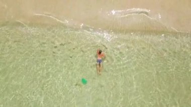 Yukarıdan kristal berraklığında deniz suyu drone görünümünde yüzen adam. Cennet plaj hava görünümünde turkuaz deniz suyunda yıkanan adam.