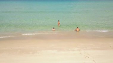 Havadan manzara insanlar rahatlatıcı ve deniz plajında kristal berraklığında suda banyo. Cennet plajında turkuaz denizde yüzen turistler.