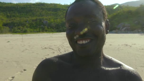 Portret szczęśliwy Afroamerykanin uśmiechając się i patrząc na kamery na plaży z bliska. Twarz przystojny mężczyzna african american na brzegu morza. — Wideo stockowe