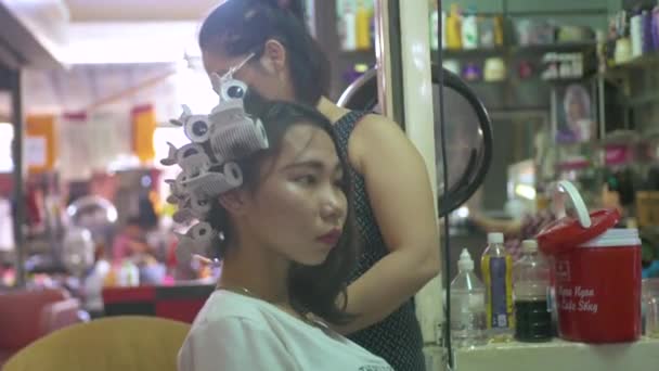 Ханой, Вьетнам - июль 2018 года: портрет вьетнамской женщины, получающей прическу и кёрлинг волос в студии красоты. Красивая азиатка в парикмахерской . — стоковое видео