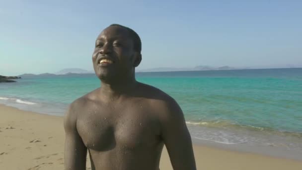 Sonriente hombre afroamericano en la playa del mar mostrando señal de victoria a los dedos. Cara guapo africano americano hombre relajarse en la orilla del mar . — Vídeo de stock
