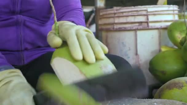 Ženské ruce pomocí nůž na loupání zralé kokosové zblízka. Žena loupání čerstvý kokos pro pití šťávy. — Stock video