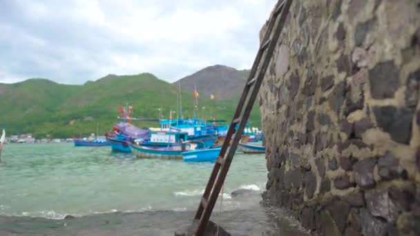 Bateaux de pêche et les navires sur le stationnement dans le port maritime sur fond de montagne verte. Bateaux de pêche traditionnels et bateaux naviguant en mer bleue . — Video