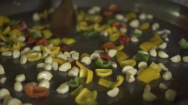 Lokanta mutfağı yemek hazırlarken sarımsak ve biber yemek Şef. Kavrulmuş sarımsak ve Bulgar biber yağda kızartma tavası, hazırlama aşçı kadar kapatın.