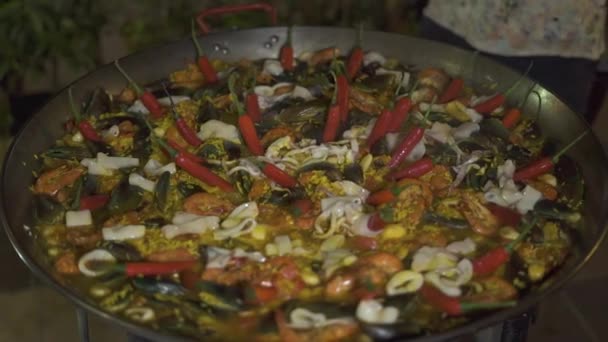 Gotowania hiszpańskiej paella z czerwonej papryki i świeże owoce morza w patelni z bliska. Przygotowaniu tradycyjnych Hiszpania jedzenie paella z małże, krewetki, kalmary i warzywa na patelni. — Wideo stockowe