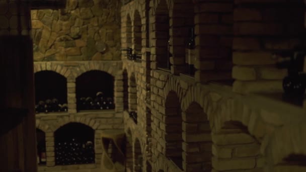 Wijn flessen liggen in stapel op kelder in taverne. Glazen flessen wijn opgeslagen in stenen kelder in restaurant. — Stockvideo