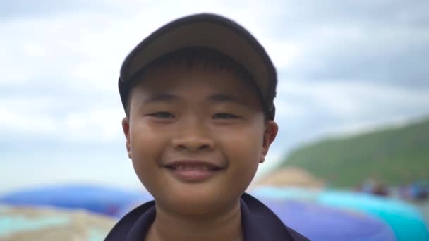 Nha Trang, Vietnam - july, 2018: portrait vietnamese boy smiling and looking into camera. Ckise up face asian boy on blue sea background. — Stock Video