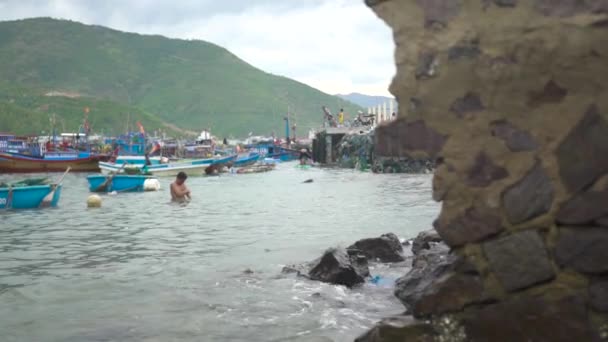 Nha Trang, Vietnã - julho de 2018: pescador que toma banho em mar azul em barcos de pesca e fundo de navios. Homens que pescam no mar e navios e barcos em segundo plano . — Vídeo de Stock