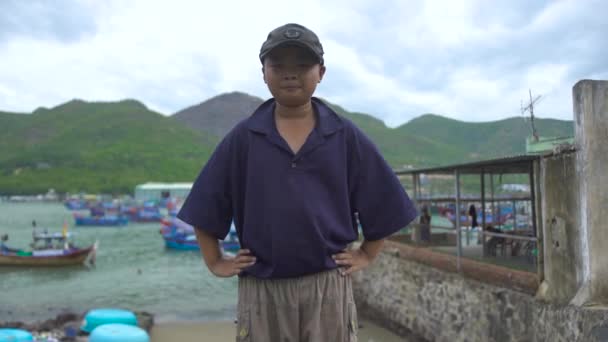 トラン, ベトナム - 7 月、2018年: 笑顔でカメラに探しているベトナムの男の子をクローズ アップ。青い海を背景にアジアの少年の肖像画. — ストック動画