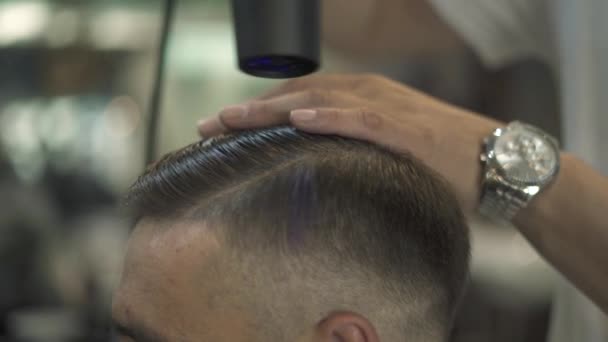 Barbeiro secagem cabelo masculino no salão de cabeleireiro. Fechar cabeleireiro soprando cabelo homem com secador na barbearia. masculino penteado fazendo penteado no estúdio de beleza . — Vídeo de Stock