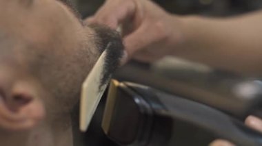 Tıraş sakallı adam elektrik kesme makinesi ve tarak erkek salonda berber. Kırpma sakal tıraş kuaför dükkanı ile kapatın. Profesyonel tıraş hipster sakal.