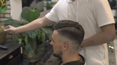 Erkek saç saç şekillendirme sırasında püskürtme berber. Kuaför berber dükkanı şık saç modeli oluşturma. Kuaför Salonu saç modeli almak sakallı adam. Erkek saç bakım kavramı.