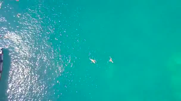 Luchtfoto mensen zwemmen in zeewater van de doorzichtige en zeilboot. Drone weergave turkoois water en toeristische mensen zwemmen rond zeilschip. Bovenaanzicht blauwe lagune landschap. — Stockvideo