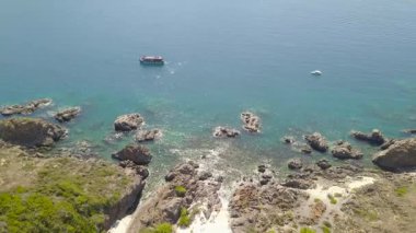 Hava mavi deniz gemi ve dağ cliff kıyı şeridi üzerinde yelken ile vurdu. Güzel manzara tekne kayalık uçurum yakın turkuaz okyanus su yelken. Berrak deniz havadan görünümü.