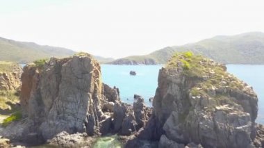 Kayalık uçurum ve mavi deniz su dron Yelkenli tekne yukarıdan görüntüleyin. Dağ cliff ve deniz hava manzara mavi lagün yelkenli gemi. Okyanus ve kayalık ada üst görüntüleme.