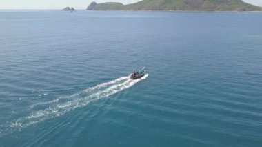 Deniz tekne üzerinde kayalık uçurum manzara mavi su içerisinde yelken. Havadan görünümü okyanusta gemi yelken. Gemi deniz ve yeşil ada peyzaj üzerinde manzarası üzerinde uçan uçak.