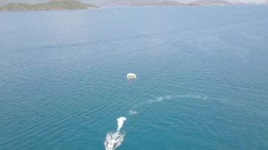 Yelkenli tekne ile mavi deniz defne dron görünümünde parasailing. Turkuaz denizde yamaç paraşütü ile yelken havadan görünümü. Güzel manzara mavi lagün ve yeşil ada.