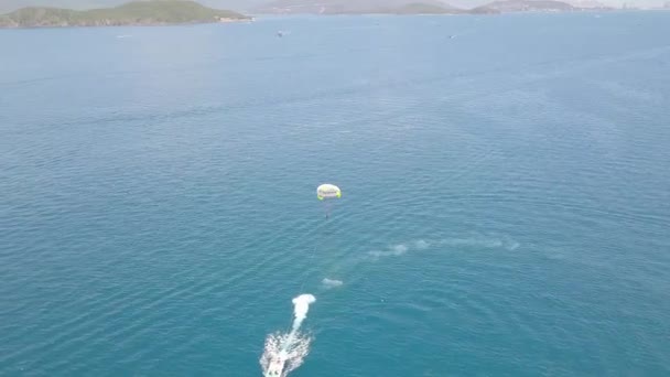 Yelkenli tekne ile mavi deniz defne dron görünümünde parasailing. Turkuaz denizde yamaç paraşütü ile yelken havadan görünümü. Güzel manzara mavi lagün ve yeşil ada. — Stok video