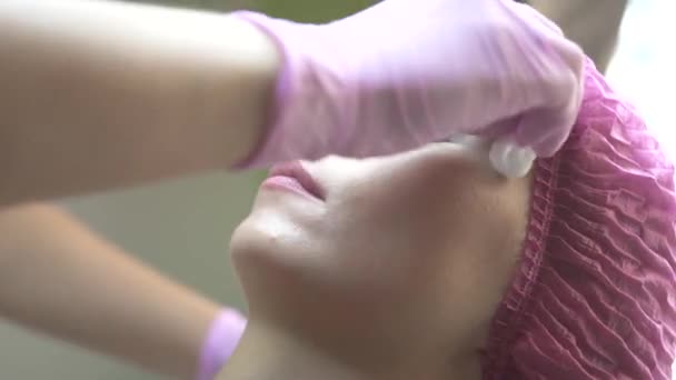 Visage jeune pendant recevoir la procédure de beauté. Médecin esthéticienne nettoyage visage patient avec éponge de coton avant la procédure de beauté. Soins de la peau et cosmétologie beauté . — Video