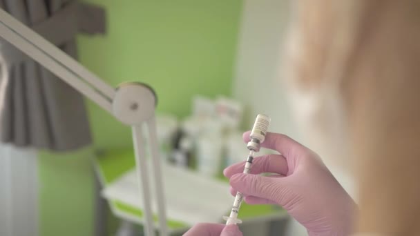 Doctor gaining medicine into syringe from glass ampule in medical clinic. Medical nurse filling syringe. Vaccination, diseases,medical care, anesthesia, euthanasia, diabetes concept. — Stock Video