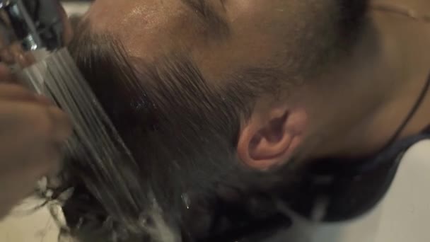 Мыть мужские волосы в парикмахерской. Парикмахер вымыл голову мужчине. Мужской парикмахерский салон. Парикмахер моет волосы молодому человеку в парикмахерской . — стоковое видео