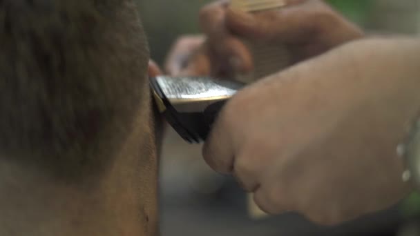 Männlicher Haarschnitt mit Elektrorasierer aus nächster Nähe. Nahaufnahme Friseur mit Haarschneider für männliche Frisur. Friseursalon mit Haarschneidemaschine. Mann schneidet Haare mit Rasiermesser. — Stockvideo