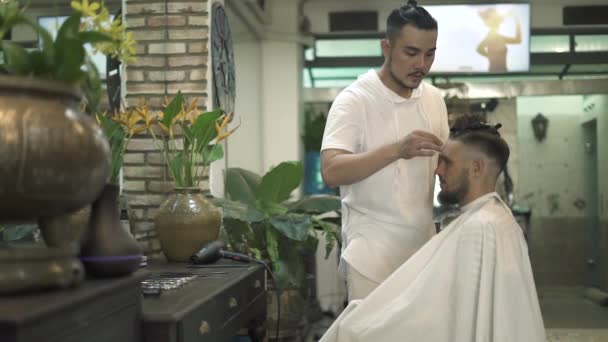 Cortador de cabelo fazendo penteado masculino com lâmina elétrica na barbearia. Um homem a cortar o cabelo no salão de cabeleireiro. Cabelo de corte cabeleireiro profissional no salão masculino. Homem cabeleireiro com elétrico — Vídeo de Stock