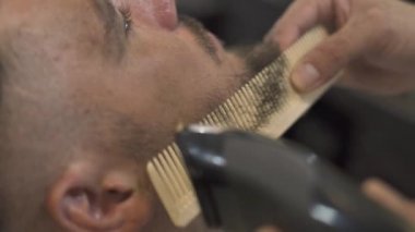 Tıraş sakal ve bıyık tıraş ve moda berber tarak. Erkek kuaför kesim sakal saç düzeltici ile kapatın. Adam erkek salonda profesyonel tıraş sakallı.