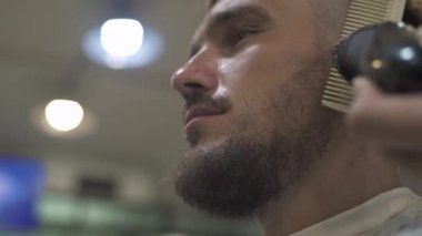 Bıyık ve sakal elektrikli tıraş makinesi ve berber dükkanı tarak ile tıraş. Erkek kuaför kesim hipster sakal ve bıyık tıraş ile yakından.