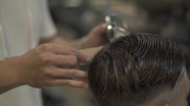 Kadeřník si stříhat vlasy s elektrickým holicím strojkem a hřeben v kadeřnictví salon. Mužské účes s vlasy stroj zblízka. Holič, dělá mužský účes v kadeřnictví. — Stock video