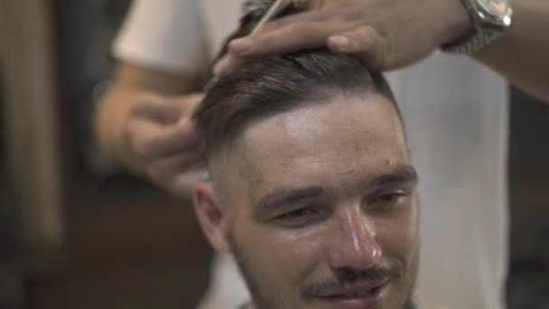 面对年轻人在理发店得到时髦的发型。Haircutter 梳头发和理发剪在男性沙龙。关闭手理发师切割湿男性头发. — 图库视频影像