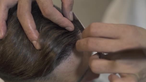 Afeitado peluquero con afeitadora recta, mientras que el corte de pelo masculino en el salón. Primer plano de afeitar el cabello con maquinilla de afeitar en barbería. Manos de hombre usando navaja de afeitar para el peinado hipster . — Vídeo de stock