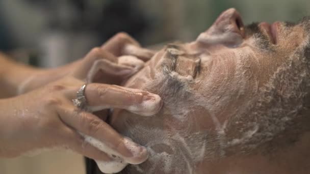 Massagiste facendo massaggio facciale e lavando la pelle nel salone maschile. Primo piano bell'uomo che riceve massaggi facciali in barbiere. Concetto di cura della pelle maschile . — Video Stock