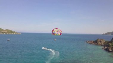 Mavi deniz üzerine uçan hava görünümünü parasail tekne çekti. Deniz koyu ve yeşil parasailing ada manzaralı dron. Yaz etkinliği ve aşırı eğlence resort kumsalda dinlenme süre