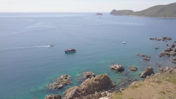 Sailing ship in blue sea water and rocky cliff aerial view. Drone shot boat sailing in sea bay and mountain cliff on shore. Top view blue ocean lagoon. — Stock Video