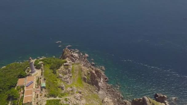 Повітряний ландшафтний світловий будинок на скелі на морському березі і блакитній воді. Маяк з видом на дрон на високій горі і красивий синій морський пейзаж . — стокове відео