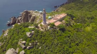 Yeşil dağ ve kayalık sahilleri, mavi deniz hava görünümünü ışık müesseseden. Kıyı ve turkuaz su ufuk peyzaj üzerinde uzun boylu dağ deniz feneri üzerinde uçan uçak.