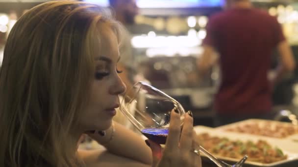 Porträt einer Frau, die in einer Bar Rotwein aus einem Weinglas trinkt. Frau trinkt bei Party in Restaurant Rotwein aus Glas. — Stockvideo