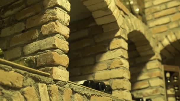 Wine cellar and glass bottles lying in stack close up. Glass bottles of red and white wine stored in stone cellar. — Stock Video