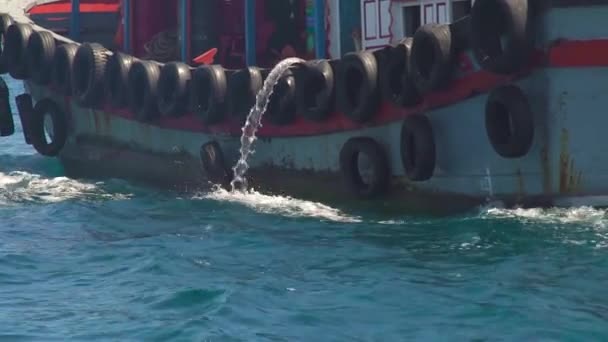 Schiff, das mit Autoreifen an Bord schwimmt, lässt Wasser im blauen Meer abfließen. schwimmendes Boot im türkisfarbenen Meerwasser. — Stockvideo