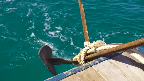 Ship anchor on ship board on turquoise sea water background close up. Sailor throwing anchor into blue sea water from board slow motion. Sailor man anchoring sailing boat. — Stock Video