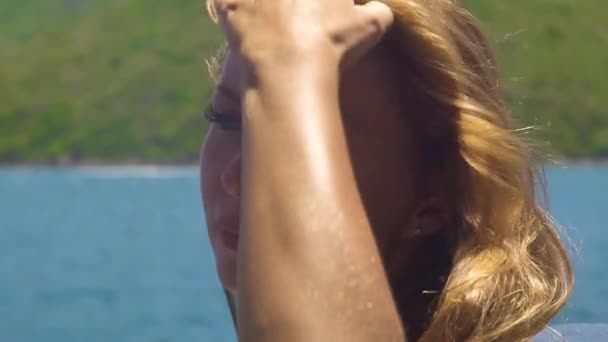 Retrato de mujer joven tocando el pelo dorado en el mar y el paisaje verde de la colina. Cara hermosa mujer con cabello castaño y dorado de cerca . — Vídeo de stock