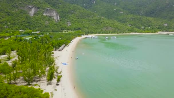 Aerial view green mountains on tropical island and sailing ship. Beautiful green island and sandy beach on shore, ships sailing in sea. Drone view from above. — Stock Video